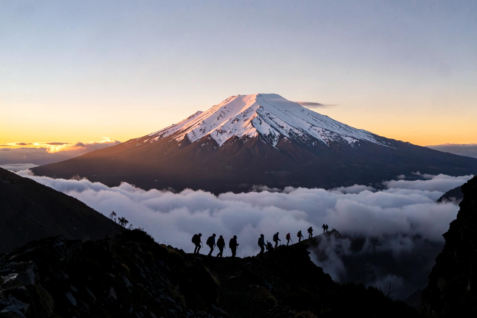 Snow capped summit of Mount Kilimanjaro at sunrise with trekkers on the ridge